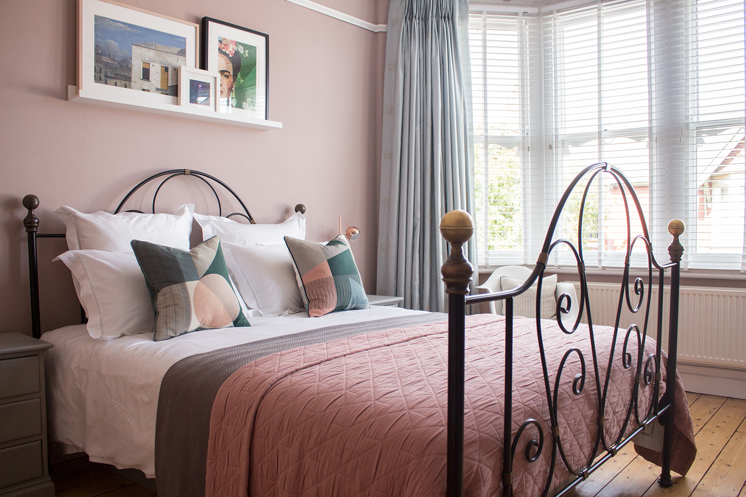 a view of the dressed bed, pink walls and blackout lined curtains