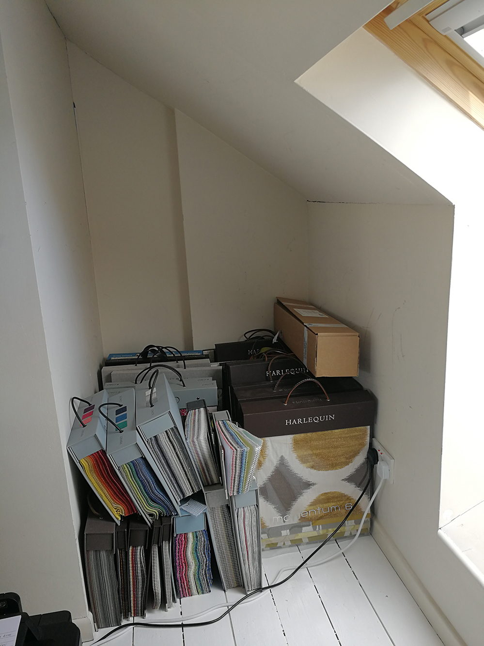 A photo of my fabric and wallpaper books all stacked up on the floor.