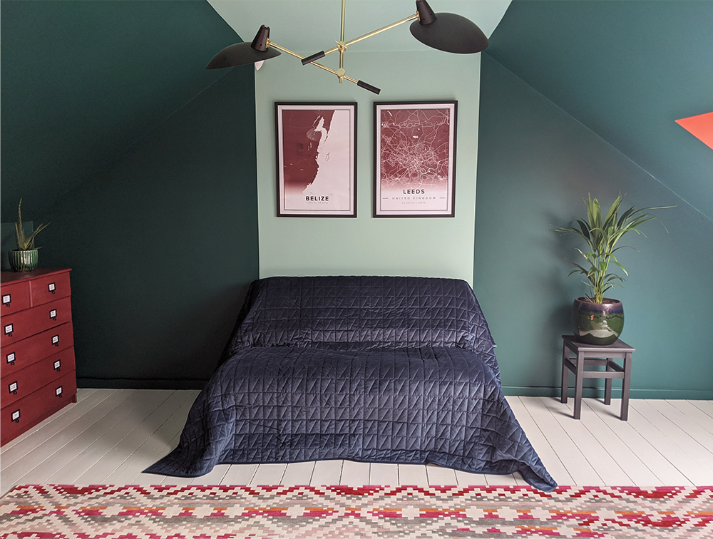 A photo of the newly decorated office, with a sofa bed and dark green walls, with a vibrant rug.