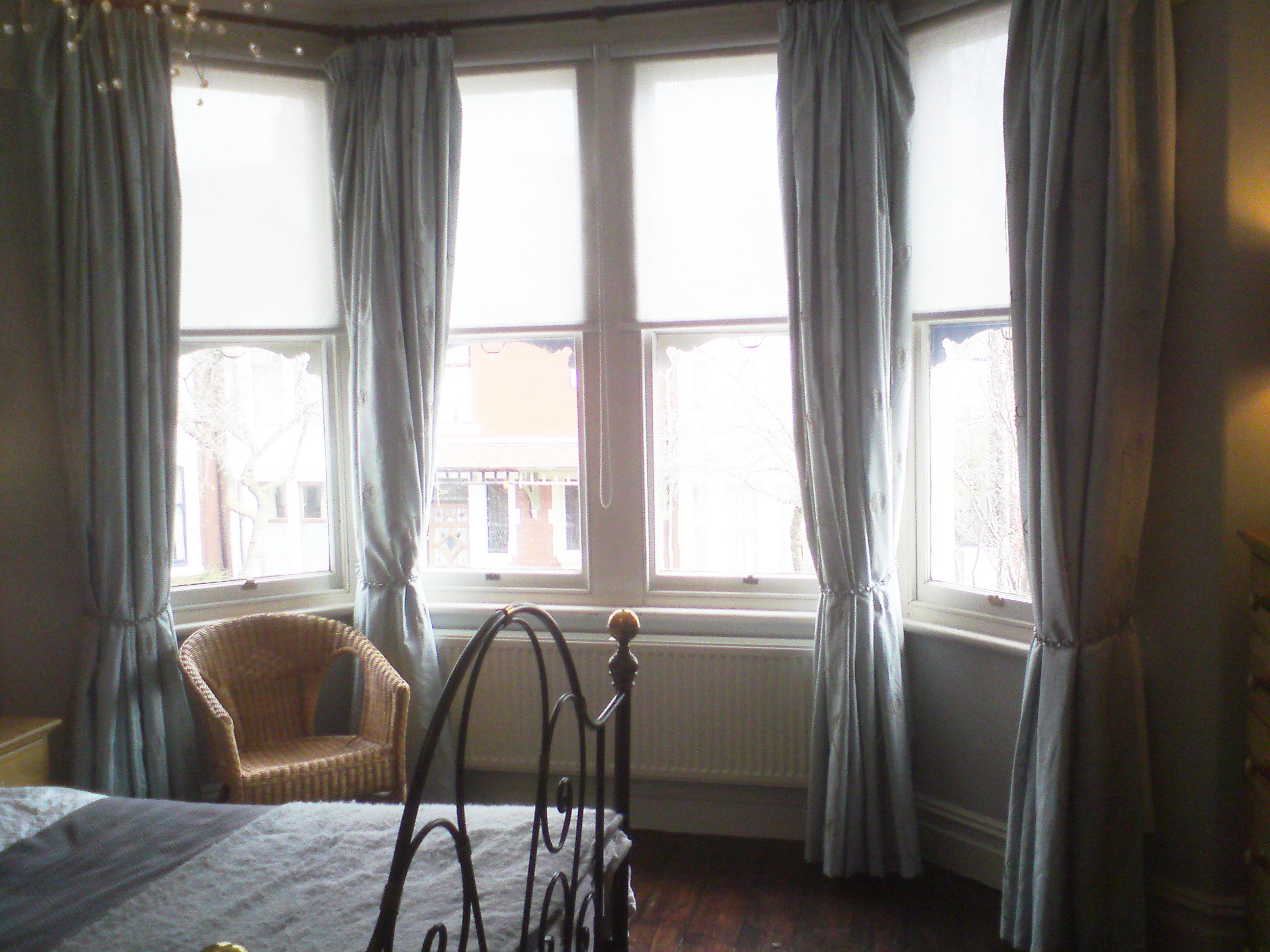 a photo of my bedroom bay window with four curtains on the old pole