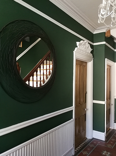 a hallway painted in a dramatic dark green with white trims
