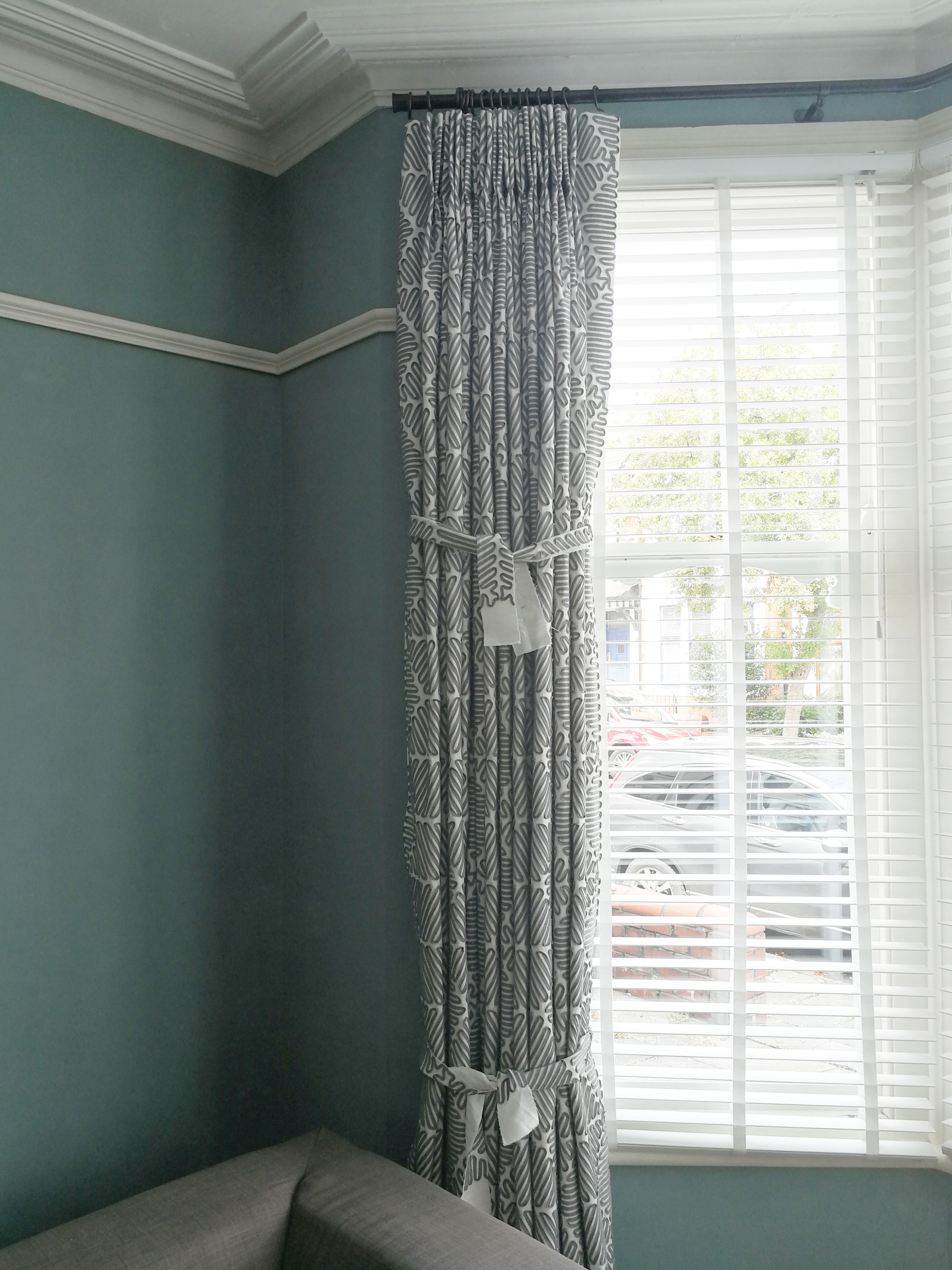 A photo of my curtains tied up in two places with fabric offcuts.