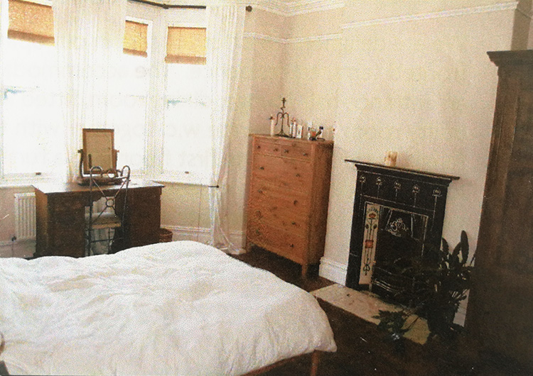 A photo of the master bedroom showing the original blinds and curtains