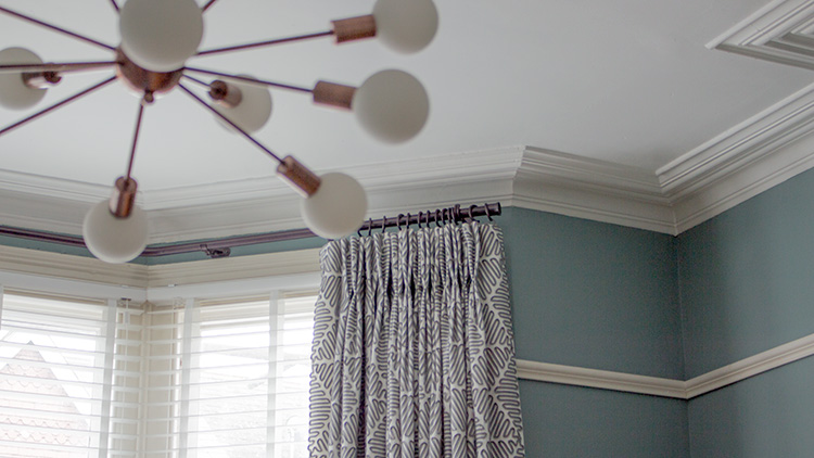 A close up photo of the new custom bent bay window pole with the curtains hung on it.