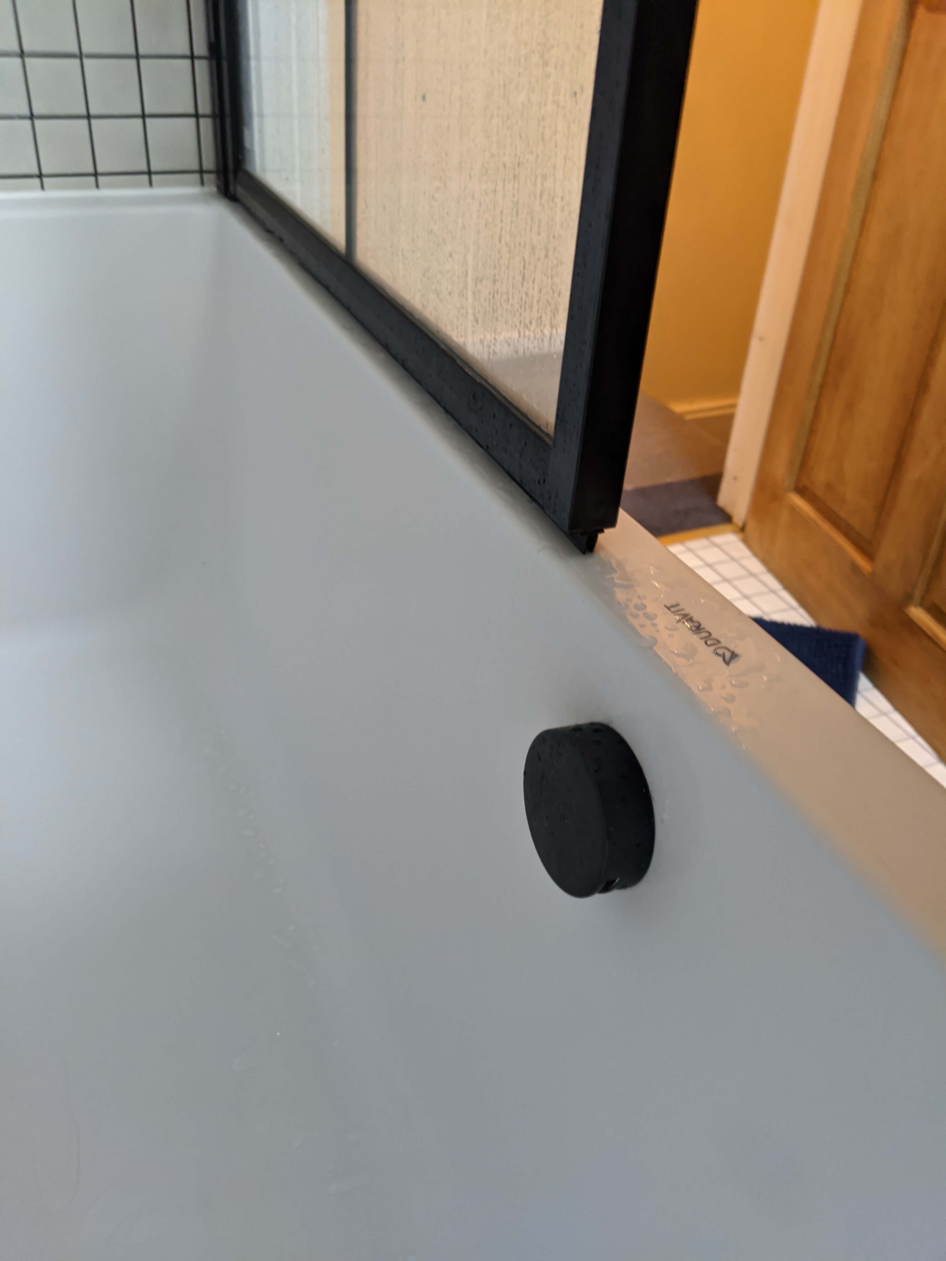A photo of the bath installed with the black overflow and filler in one.