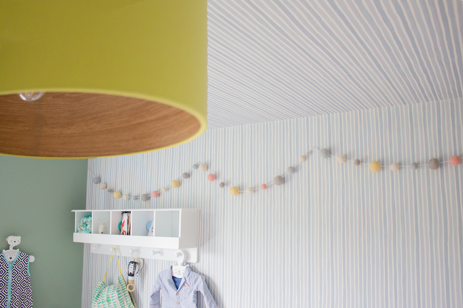 A photo of the nursery shwoing the striped wallpaper going up one wall and continuing on to the ceiling.