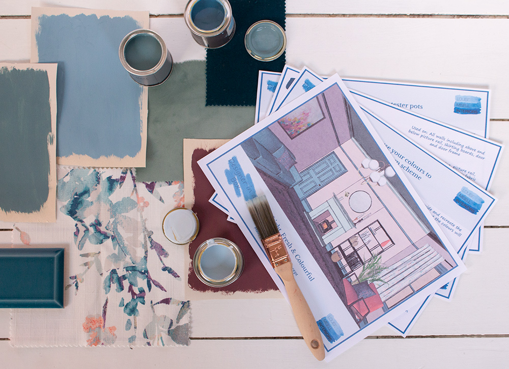 A photo of the paperwork included in Designer in a Box with paint and fabric samples around it.