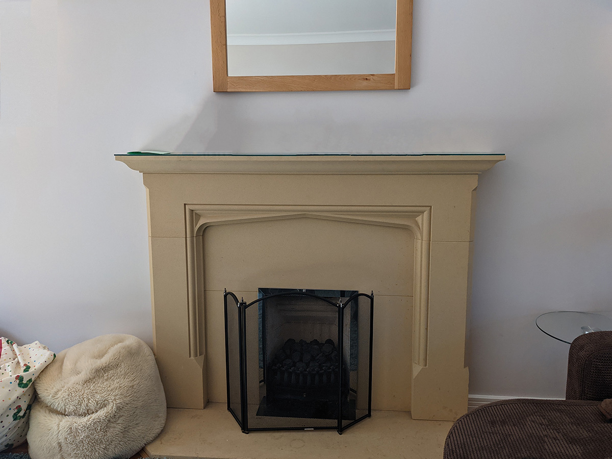 the current fireplace which is made of fake limestone and too large for the room.