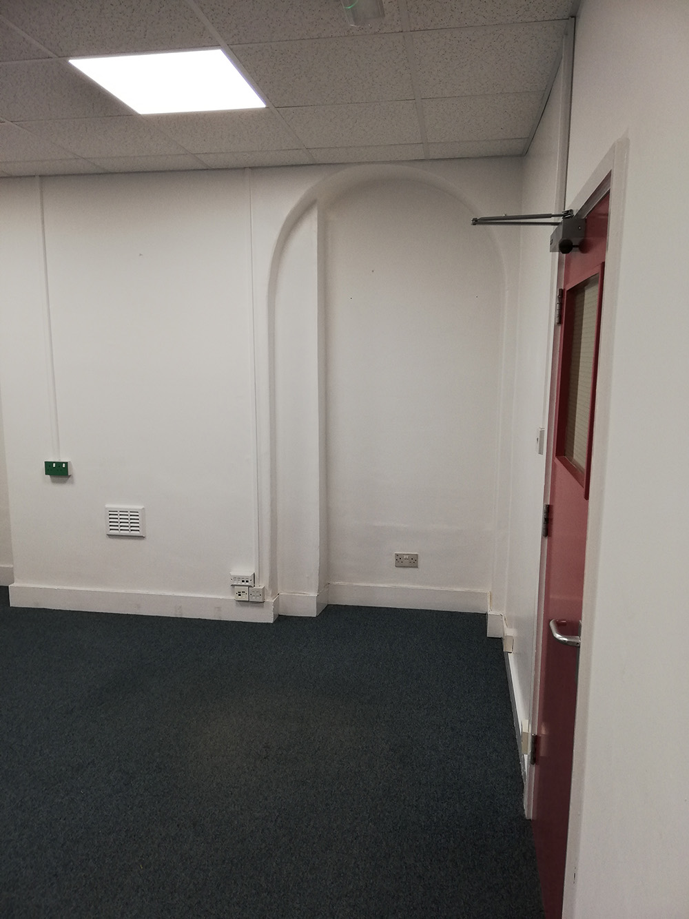A photo of the office before it was decorated showing the alcove and the door.