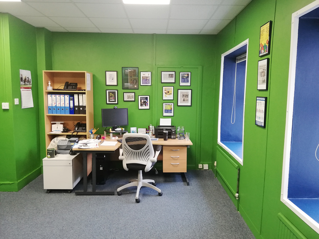 A photo of the finished office showing the green walls and blue frames around the windows.