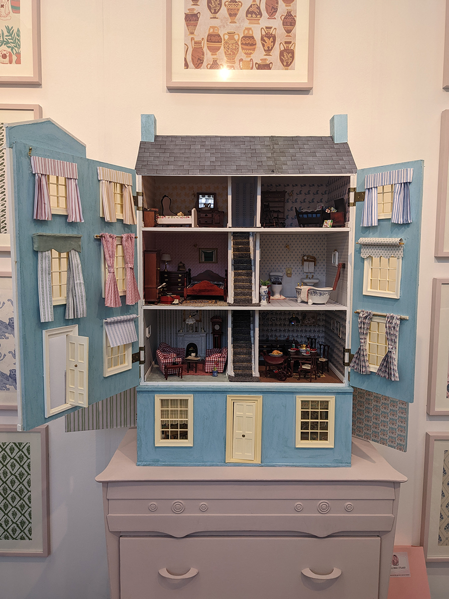 A photo of a doll's house decorated with fabric and wallpaper from the Annika Reed collection
