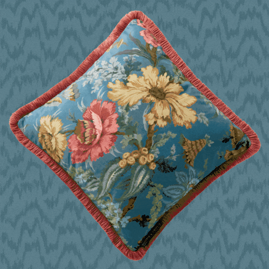 A photo of one of the new cushions from Woodchip and Magnolia, in blue with a red fringe.