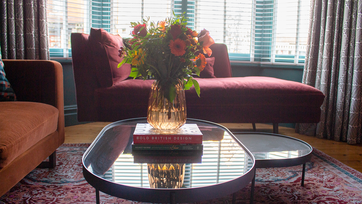 A photo showing the curved coffee tables and the ribbed glass vase of flowers on top.