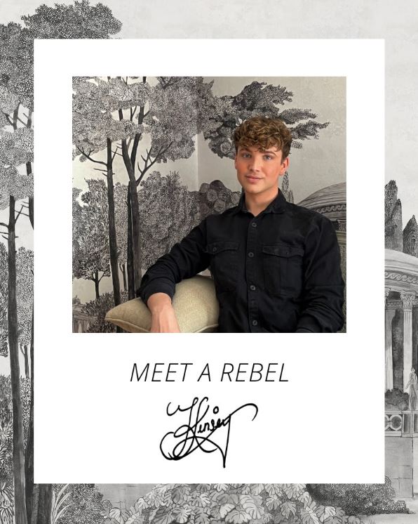 A photo of Jack Kinsey in front of one of his wallpaper designs from Rebel Walls.