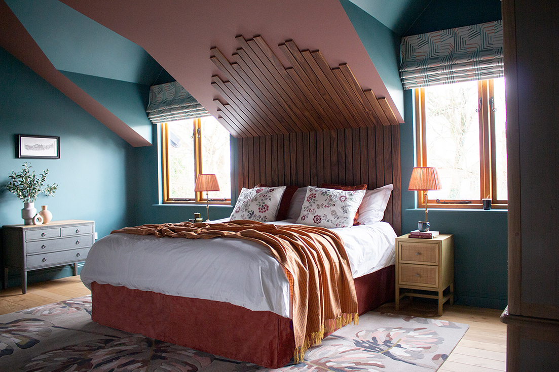 bedroom with blue walls featuring a double bed with wooden headboard 