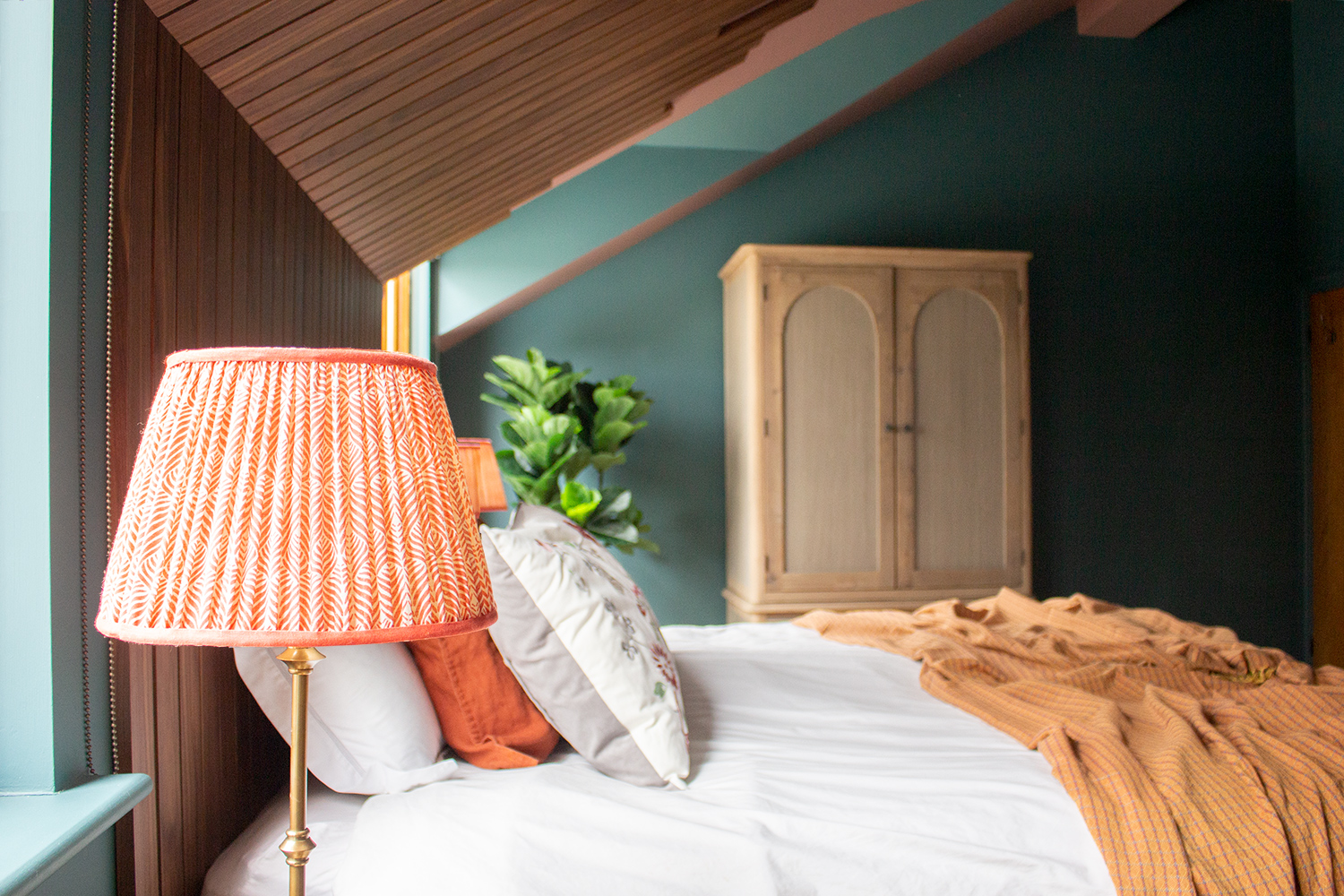 coral lampshade next to a double bed 