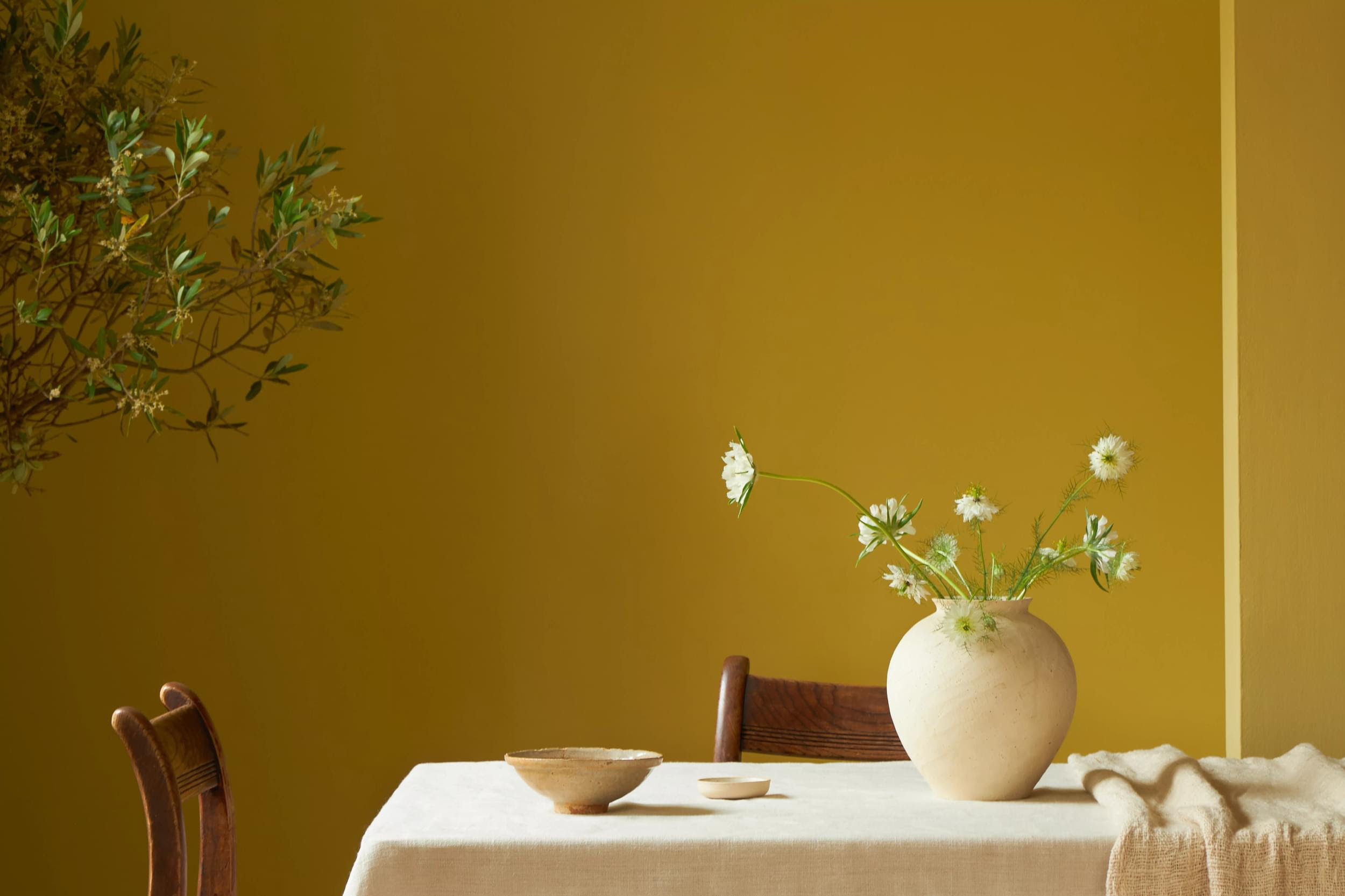 A photo of a mustard yellow painted wall with a dressed table in front of it.