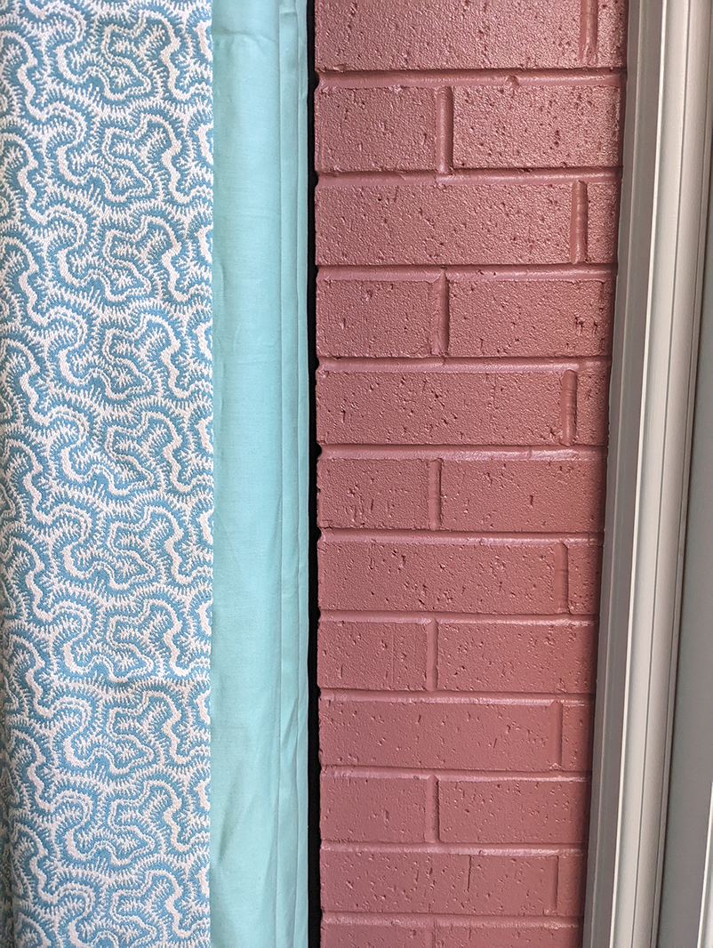 blue curtains and a pink brick wall 