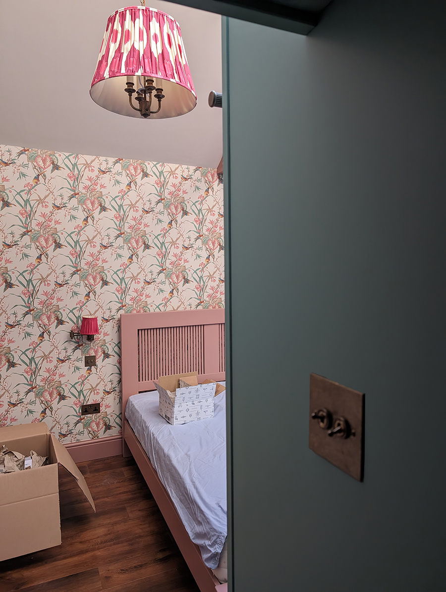 A photo of the bed which has been painted in the same pink as the skirting boards.