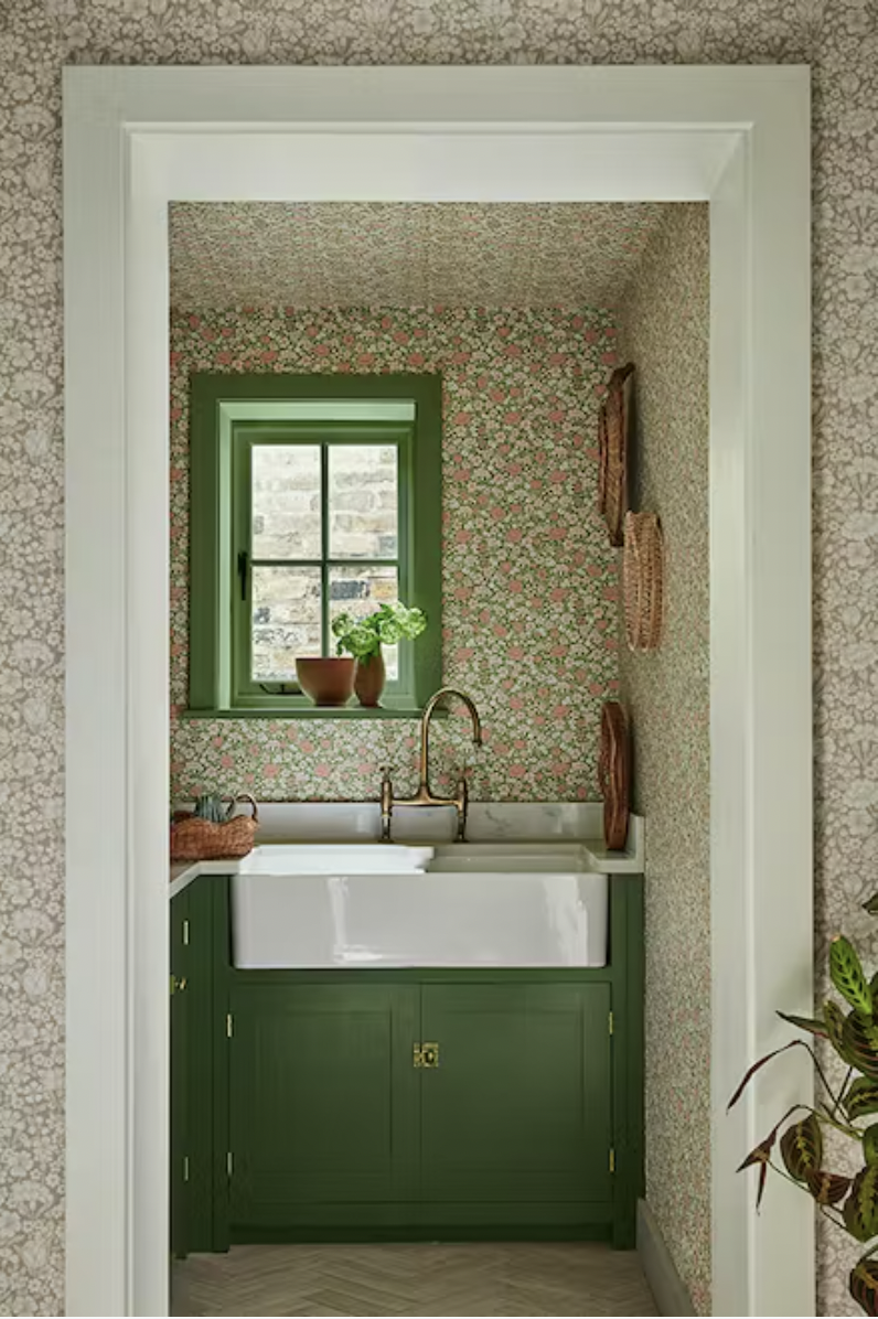 a pantry room with green cupboards. The walls and ceiling are covered in green floral wallpaper