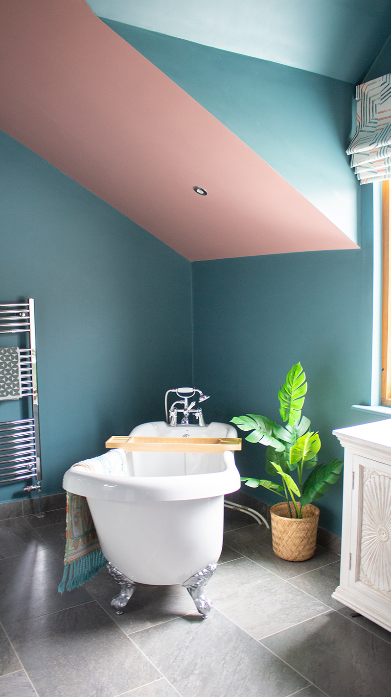 A photograph of a bathroom with teal walls and a white bath 