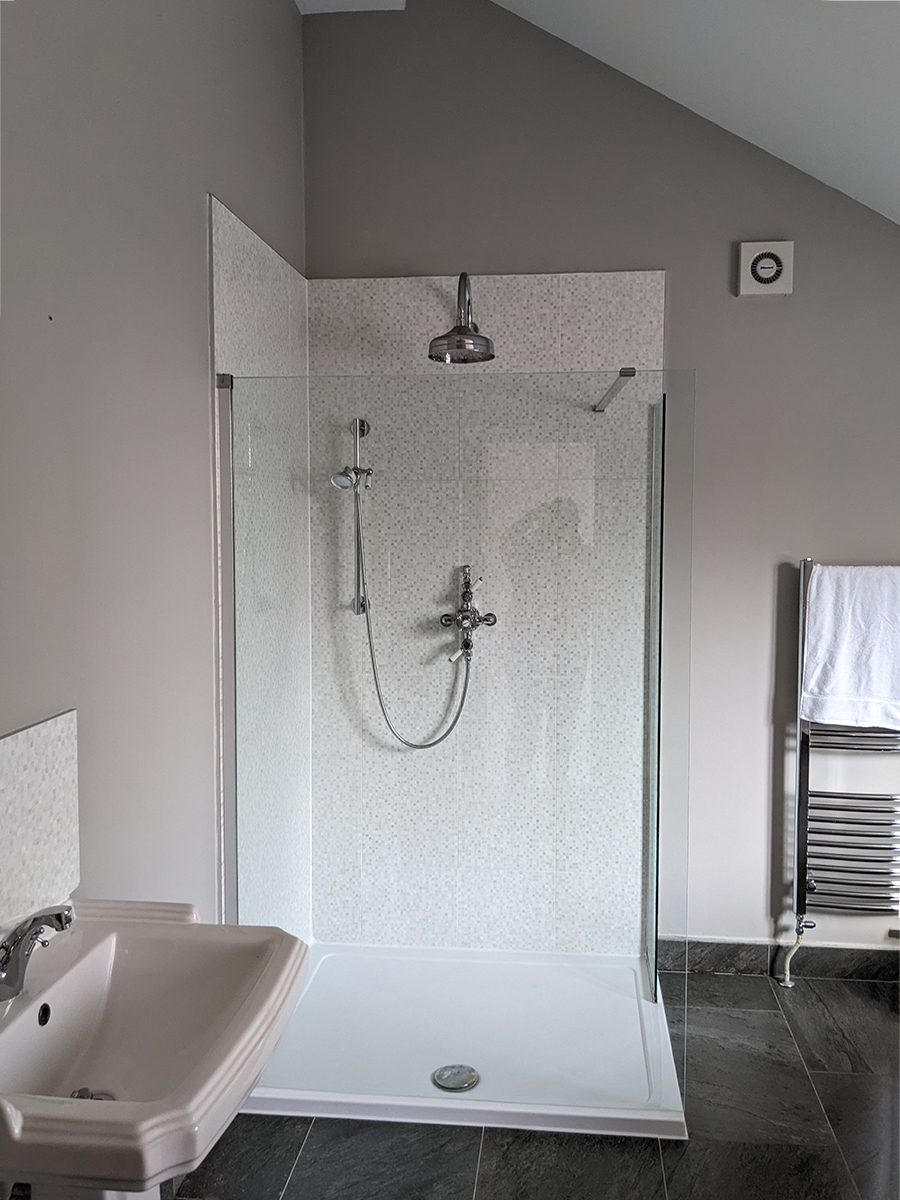 A photograph of a bathroom with grey walls and a white tiled shower 