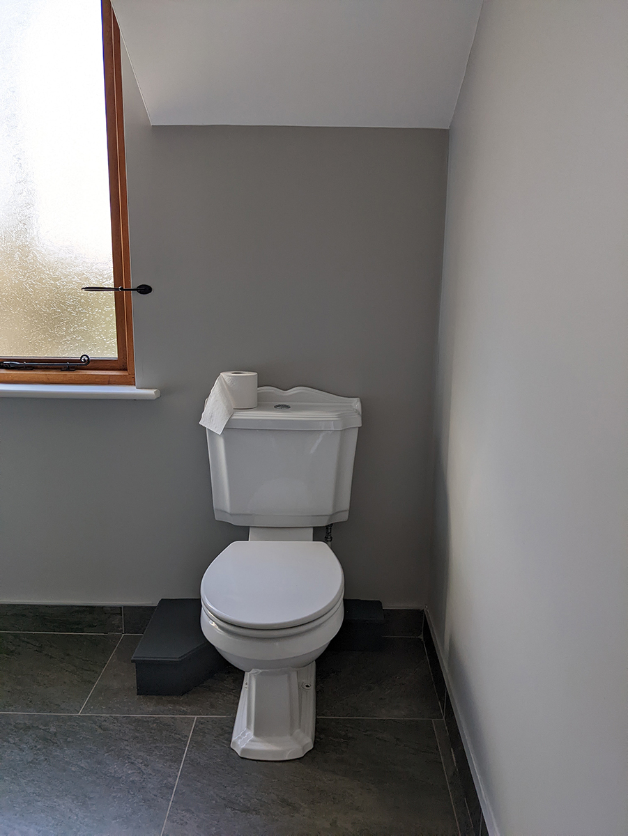A photograph of a bathroom with grey walls and a white toilet 