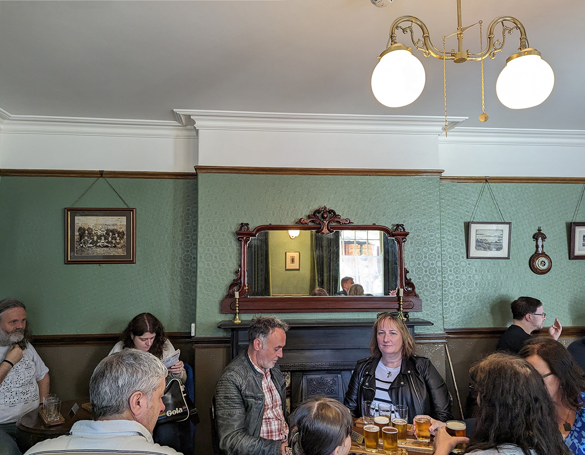 A green room with a wooden victorian fireplace 