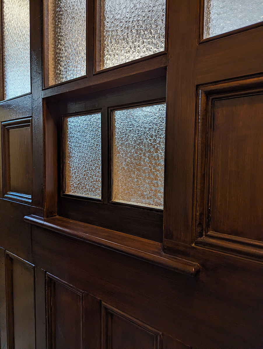 A panelled wall with a glazed hatch 