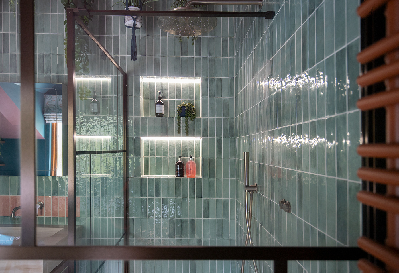 A photo looking through the shower screen to the shower niches which have LED lighting in them.