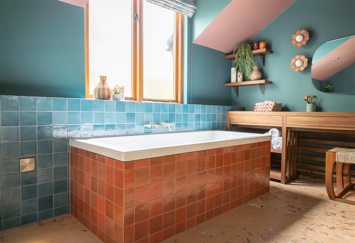 A photo showing the coral tiled bath surround and the bath under the window.