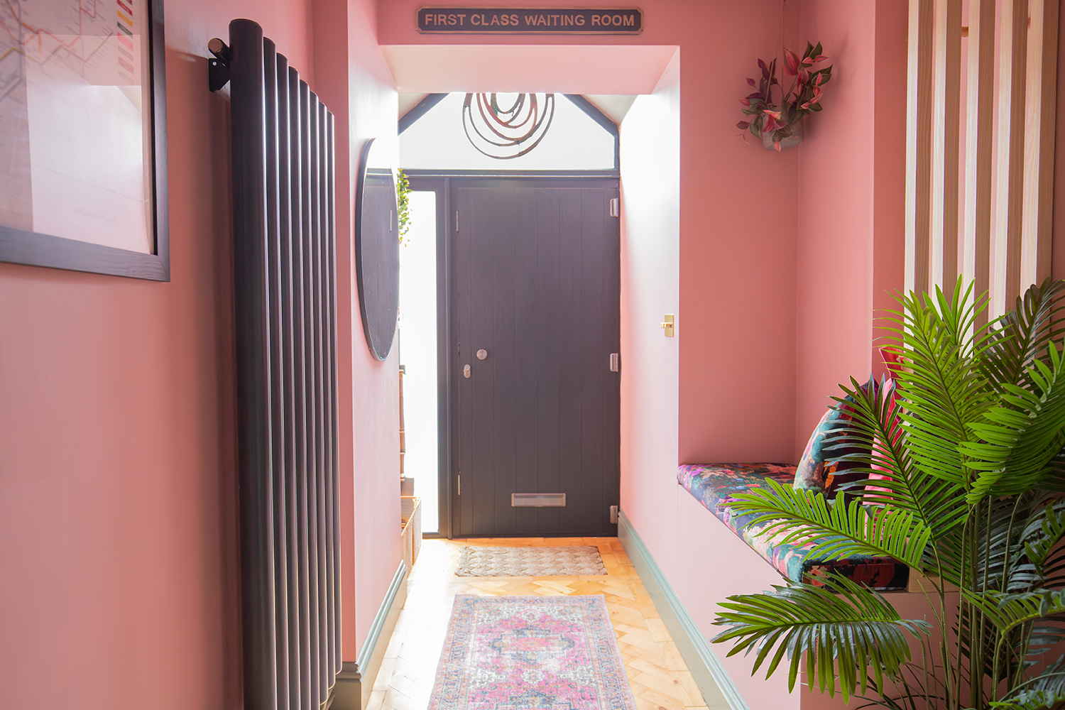 A pink hallway with a black front door 