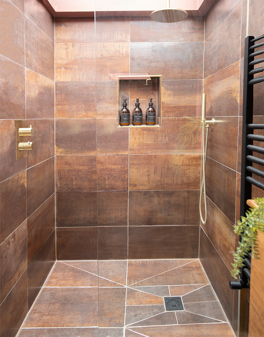 A shower cubical with bronze tiles and brass hardwear 