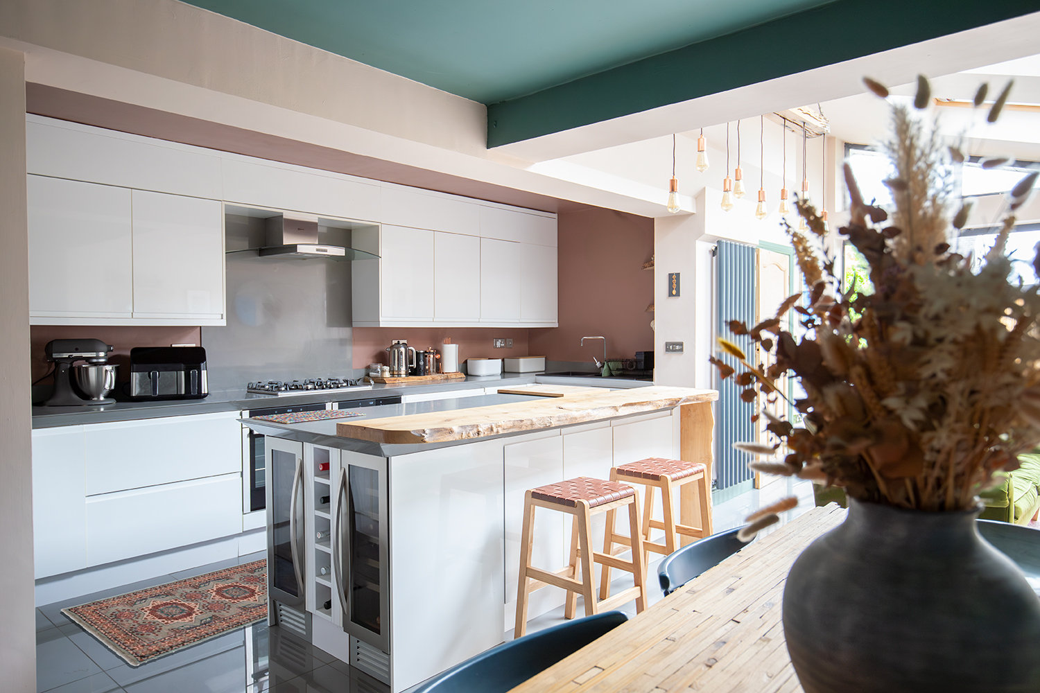 A kitchen with white cupboards and pale pink walls 