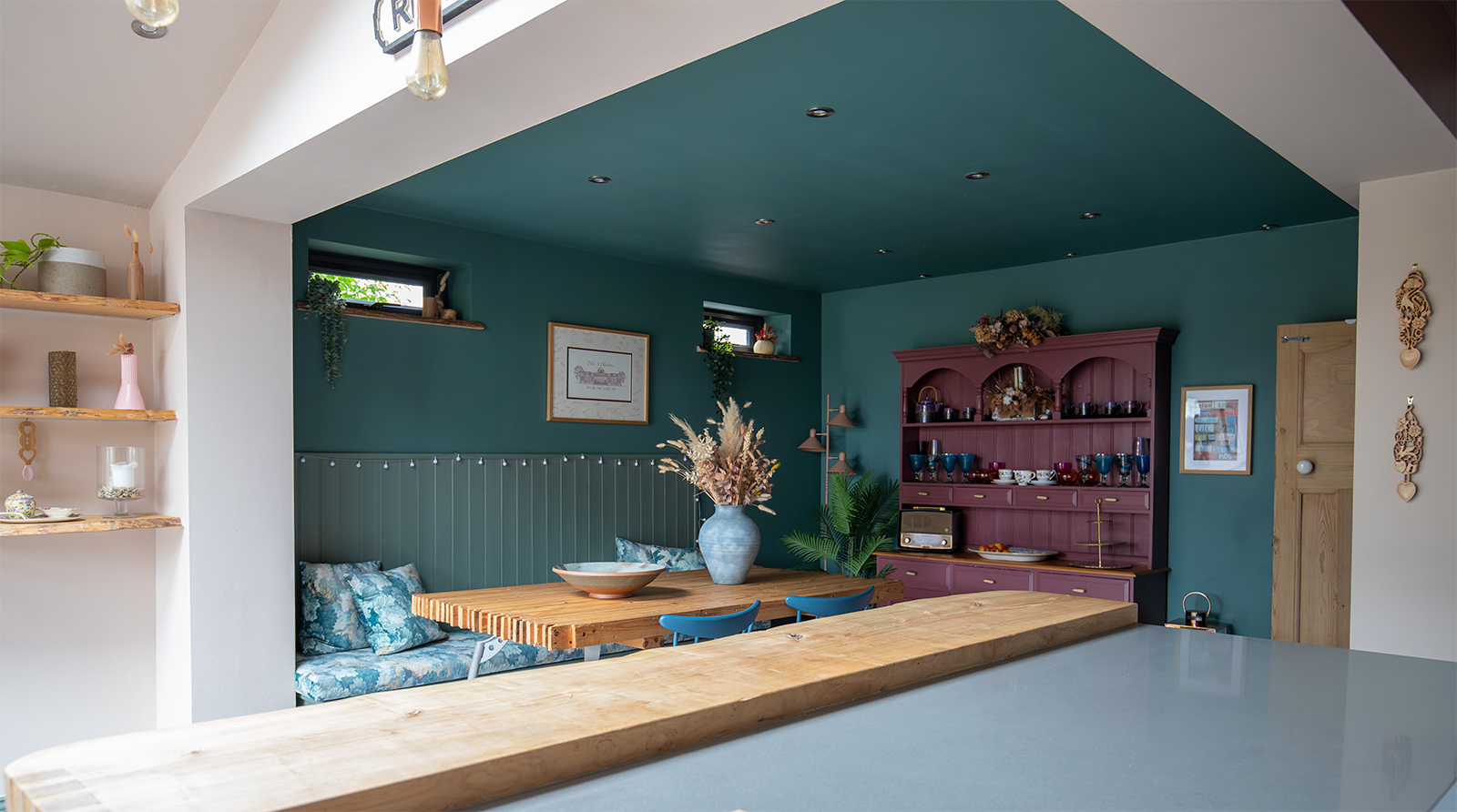 A dining area with dark teal walls and built in seating