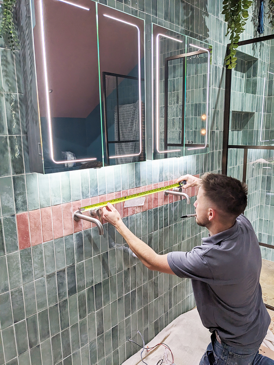 A carpenter installing a sink unit in a bathroom 