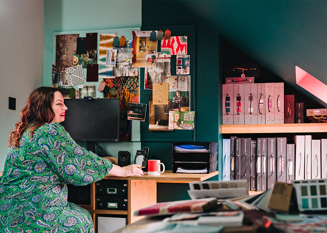 A women sat at a desk looking at fabric and wallpaper samples 