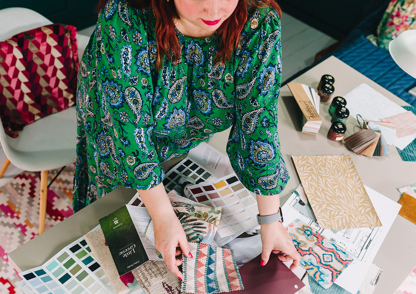 A womens hands looking through paint charts on a desk 