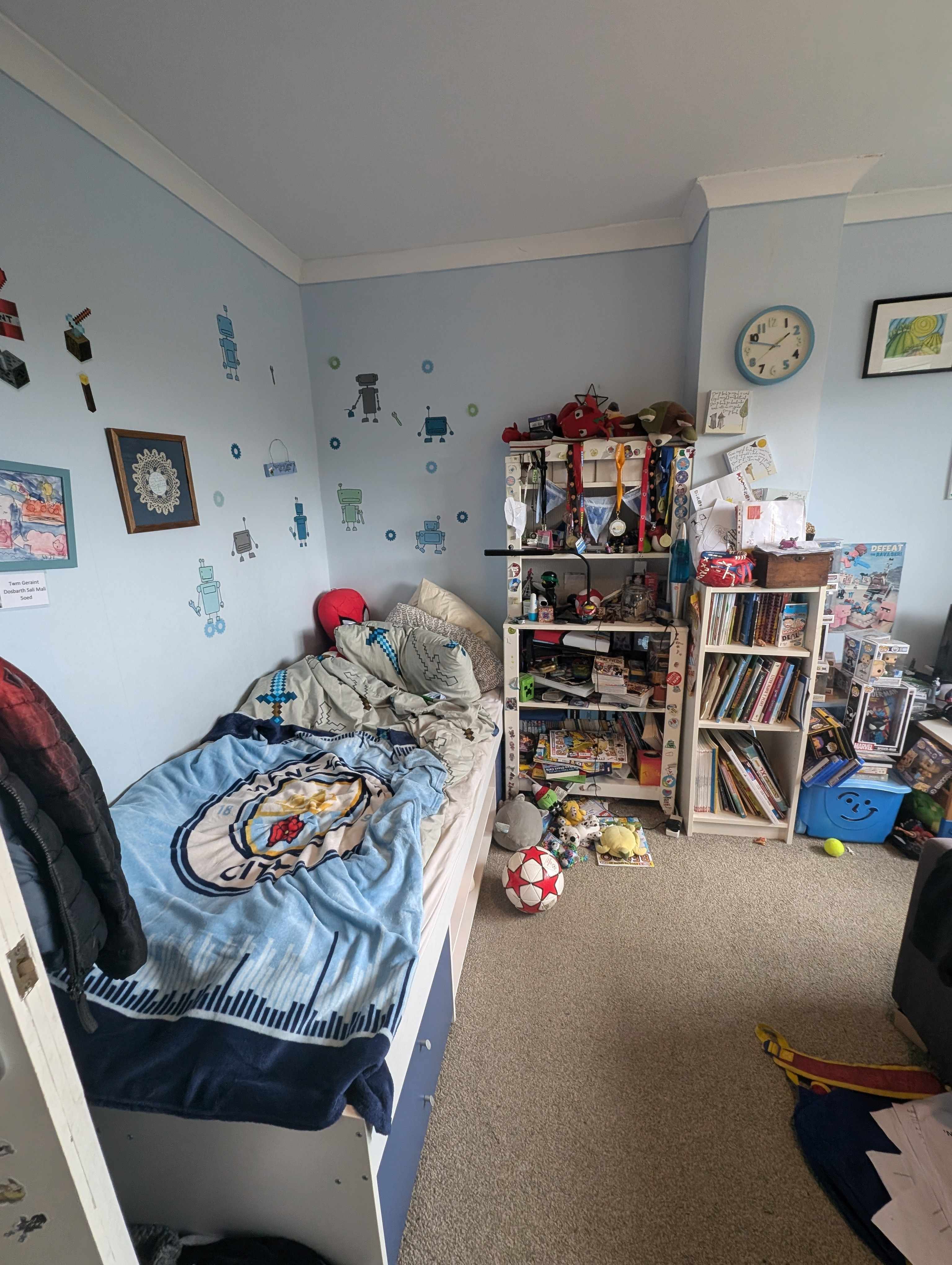 A photo of a boys bedroom with blue walls and lots of books 