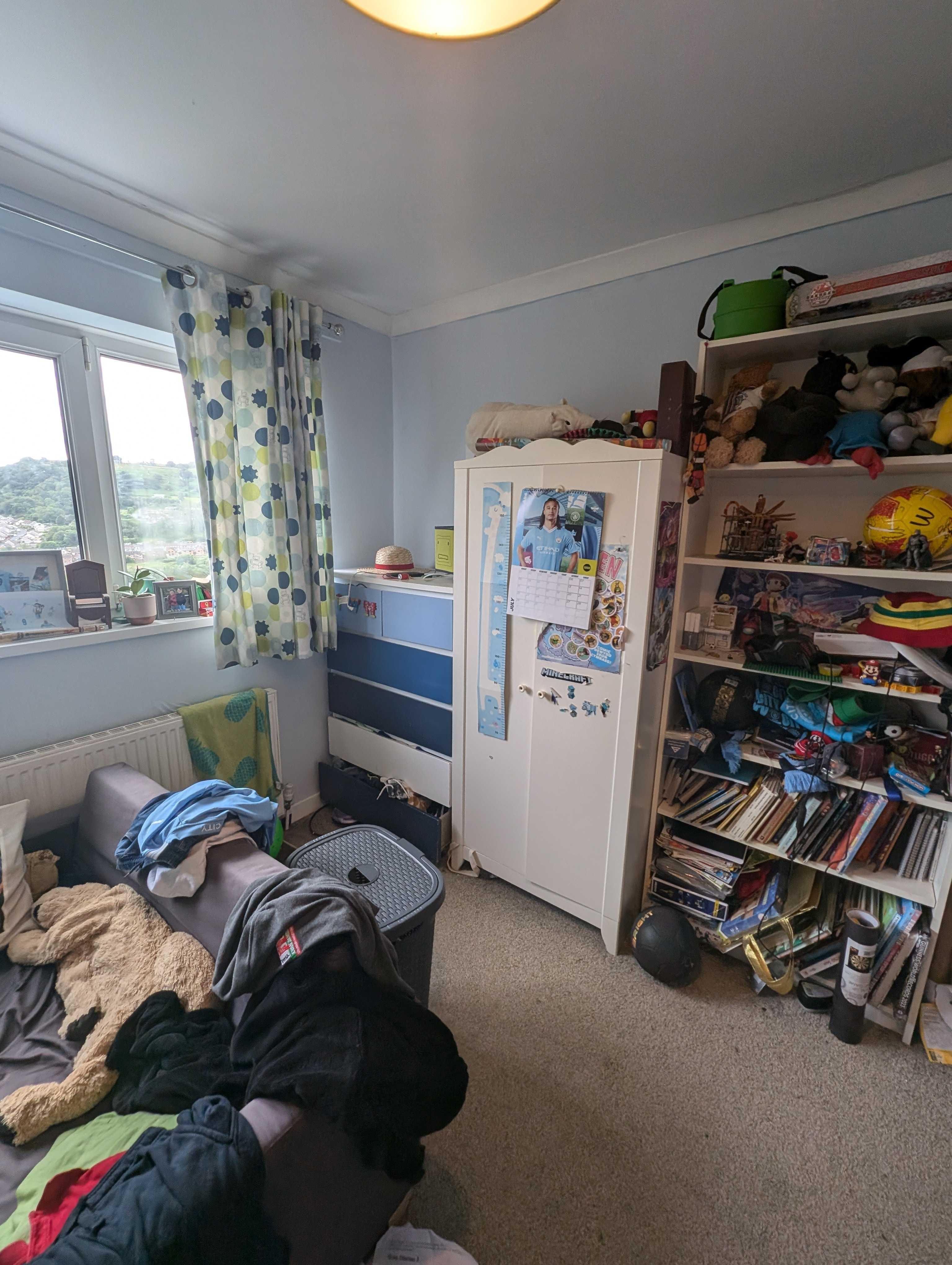 A photo of a boys room with blue drawers and wardrobe 