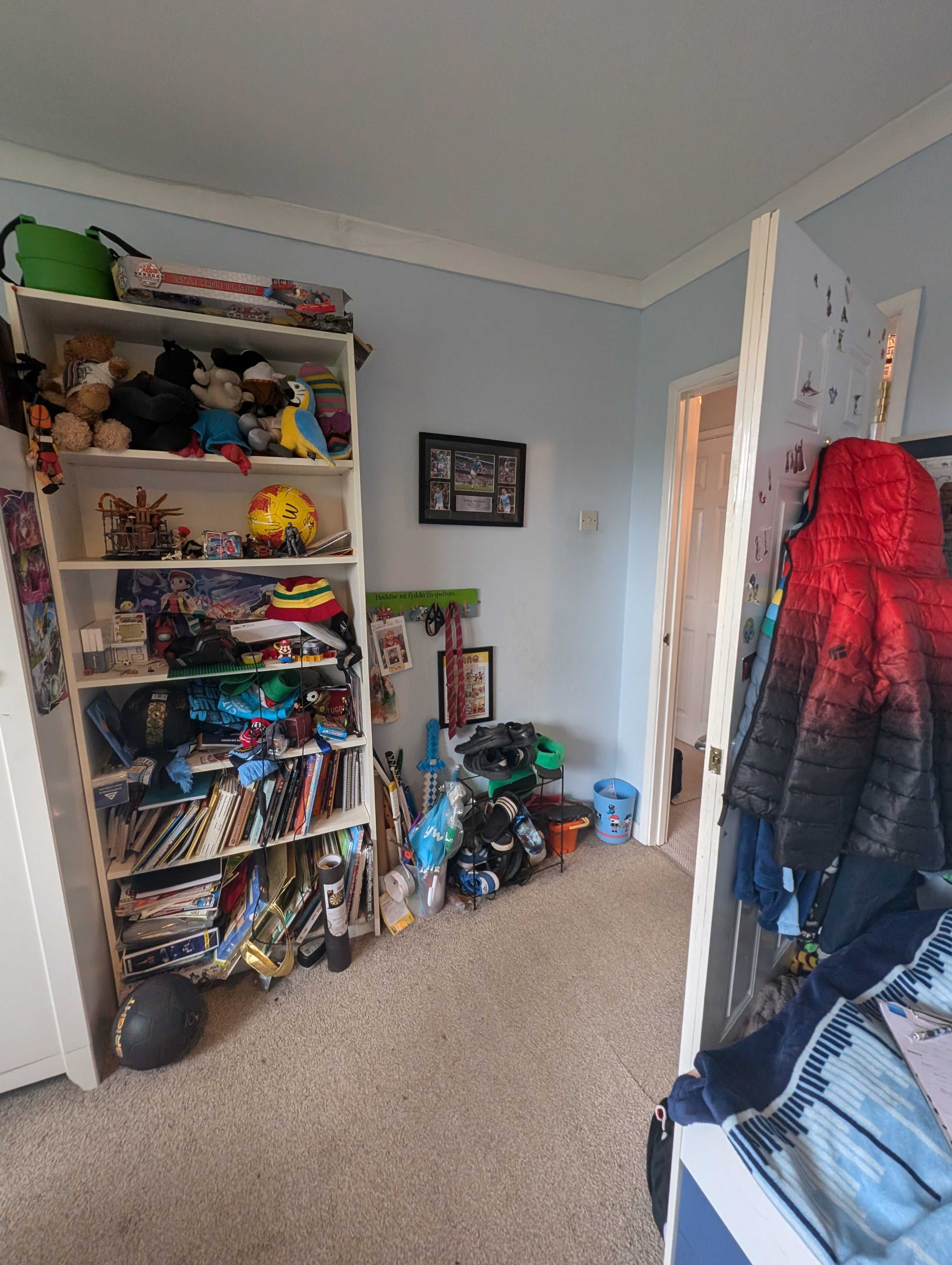 A photo of a boys room with bookcase full of toys and books 