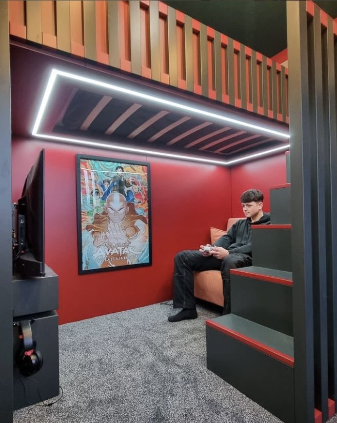 A young boy sat in an orange chair holding a gaming console 