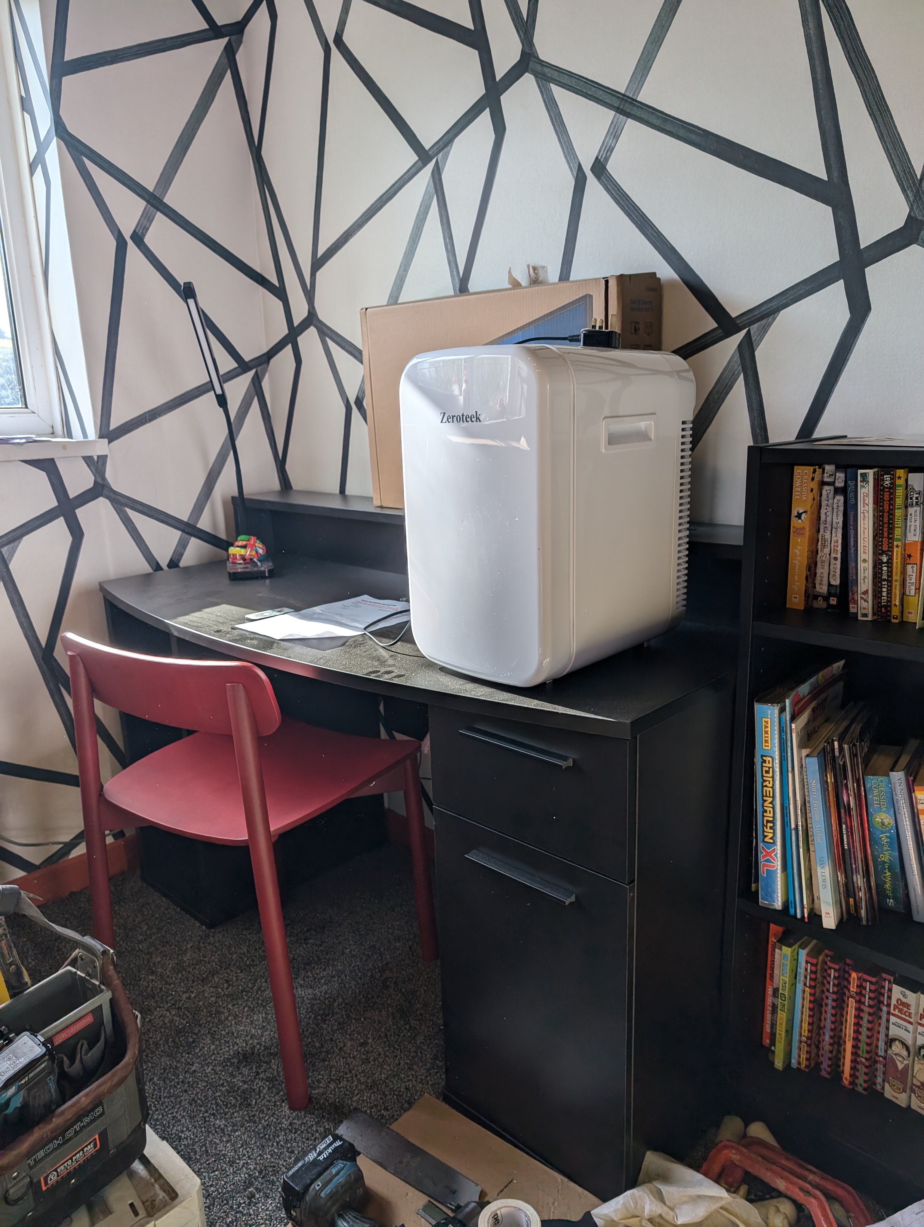 A black desk and white mini fridge 