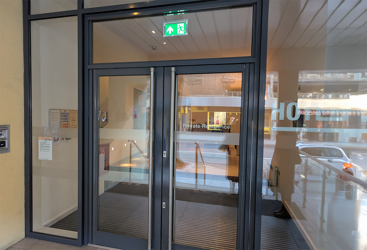 A photo of the outside of the lobby showing the hotel sign on the door.