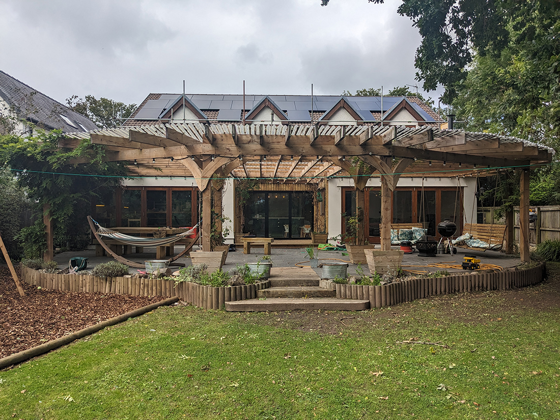 A photo of a detatched house with a large wooden pergola which has a plastic roof