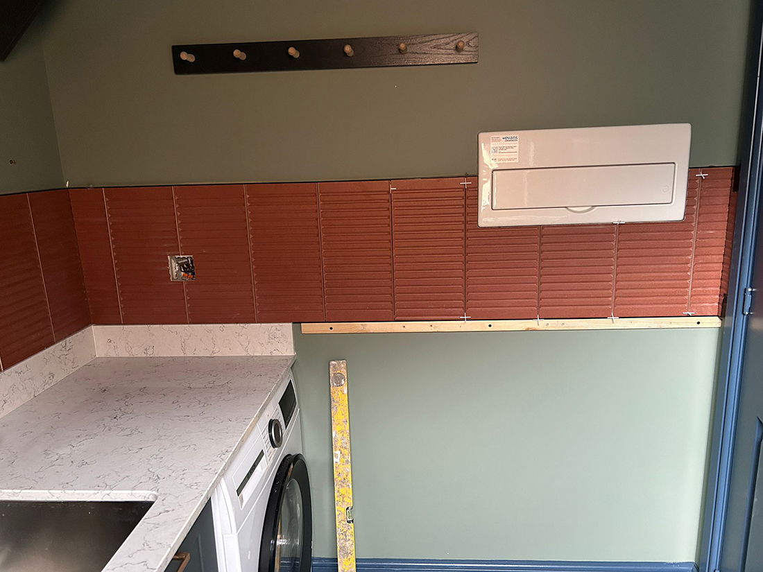A utility room with green walls and terracotta tiles 