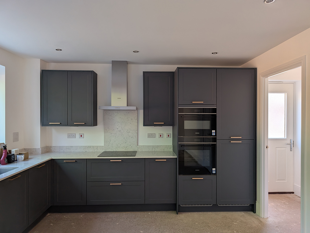 A kitchen with dark green cabinets and white walls 