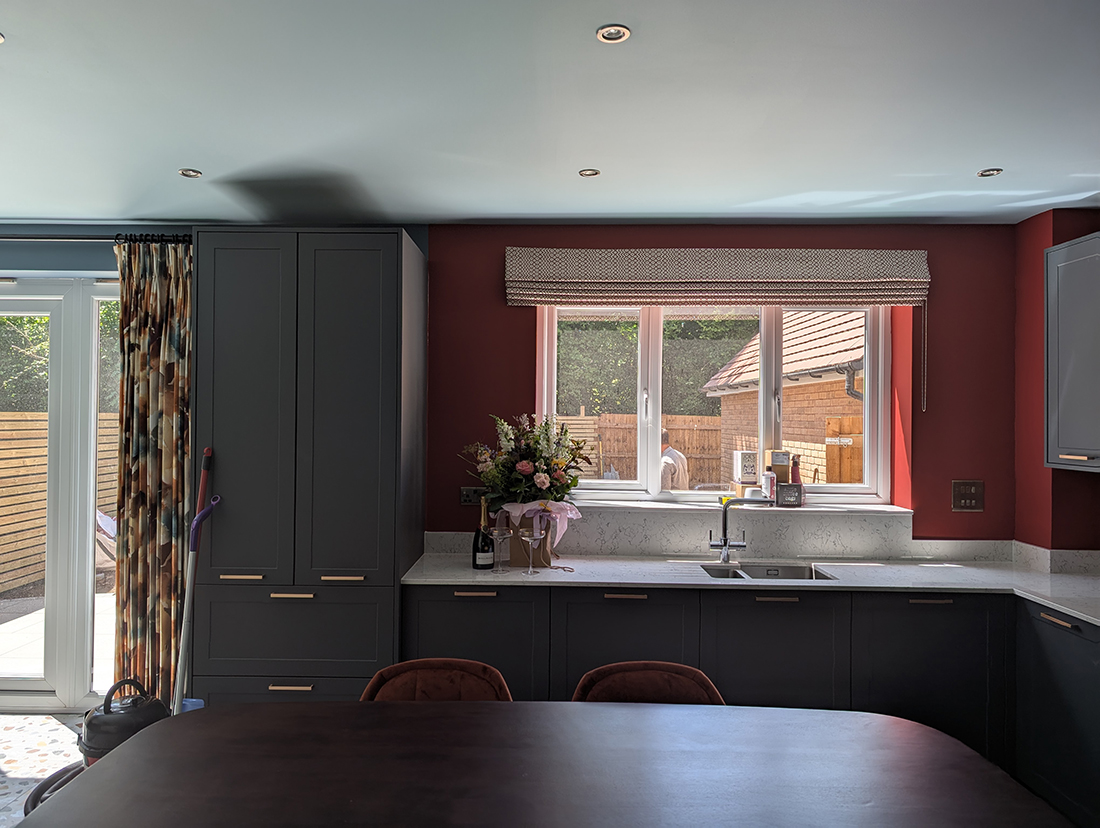 A kitchen with dark green cabinets and red walls 