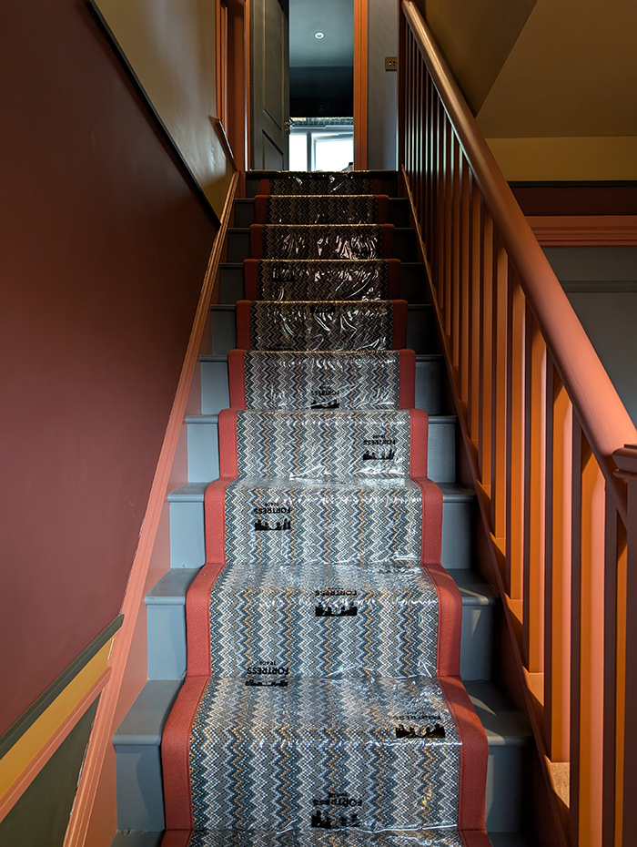 A staircase with a patterned runner and red walls 