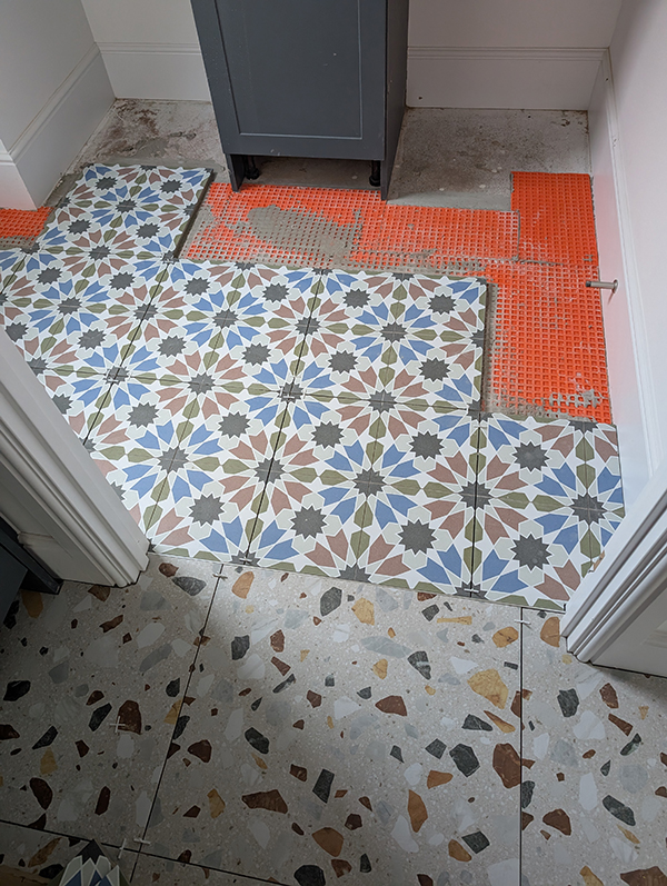A photo of blue and green patterned floor tiles being laid 